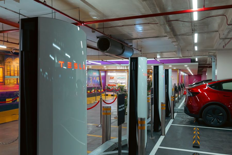 Tesla V4 Supercharger posts in a shopping-center parking structure